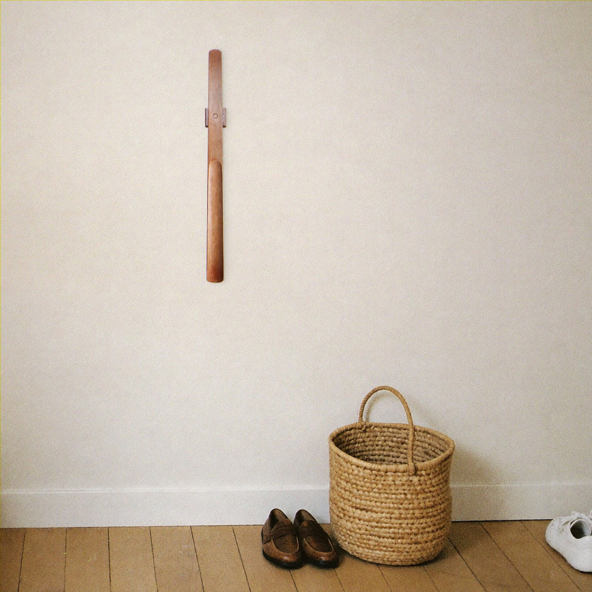 The wooden shoehorn on its magnetic mount in a calm, tidy entryway
