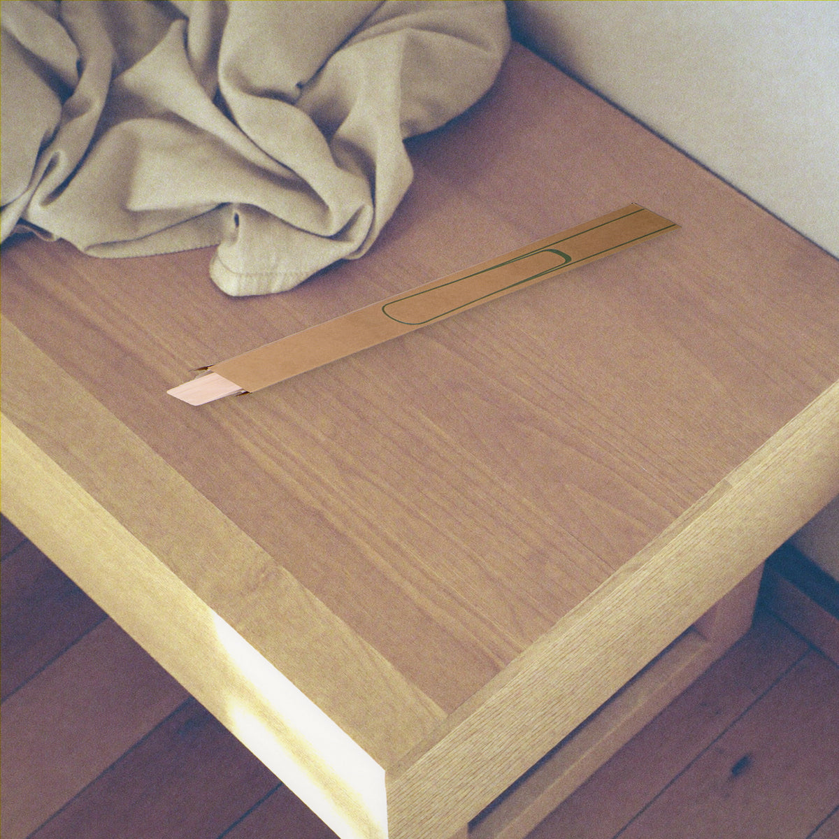 The shoehorn in its kraft gift sleeve resting on a pale oak entryway bench