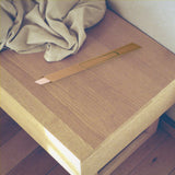 The shoehorn in its kraft gift sleeve resting on a pale oak entryway bench