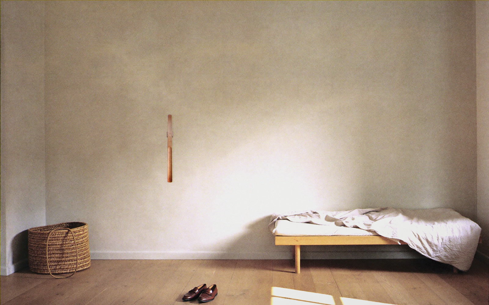 The shoehorn hanging on a plaster wall in a wide, calm Scandinavian entryway
